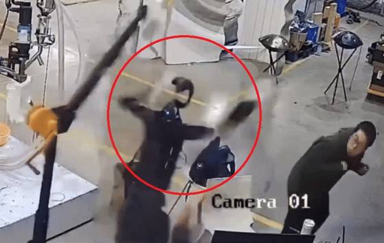 중국의 한 연구소에서 미니 크레인에 매달린 휴머노이드 로봇이 오류 행동을 보이자 놀란 연구원이 몸을 피하고 있다. 사진 SNS 캡처