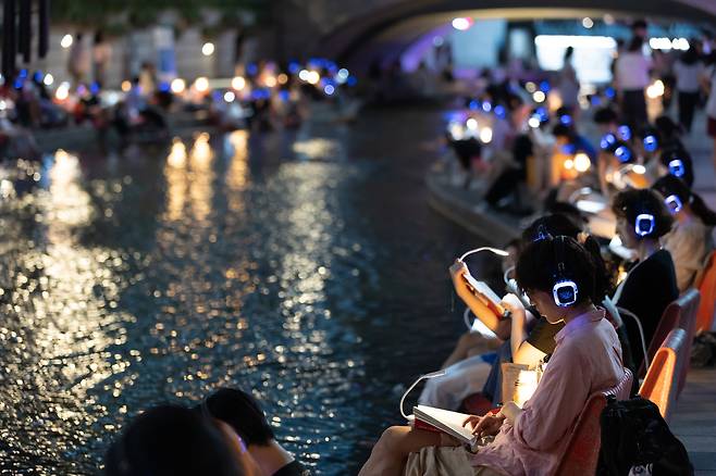 People read books at an outdoor library, which opened along the Cheonggye Stream in central Seoul in 2024. (Seoul Metropolitan Government)