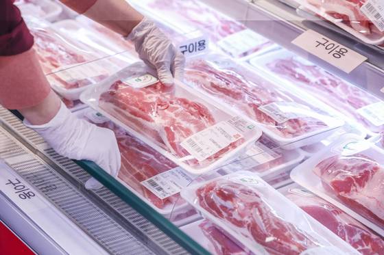 An employee arranges pork belly servings at a large supermarket in Seoul on April 13. [NEWS1]