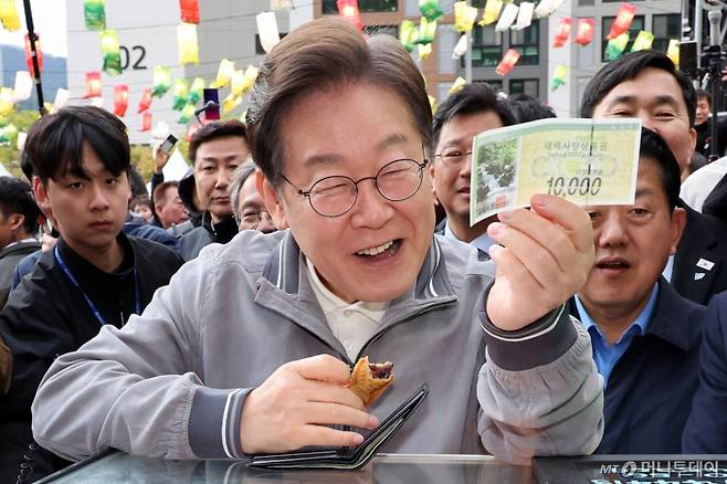 [태백=뉴시스] 조성우 기자 = 민심을 청취하는 '경청 투어'에 나선 이재명 더불어민주당 대선후보가 3일 강원도 태백시 장성중앙시장에서 잉어빵을 구매하기 위해 태백사랑상품권을 꺼내 보이고 있다. 2025.05.03. xconfind@newsis.com /사진=조성우