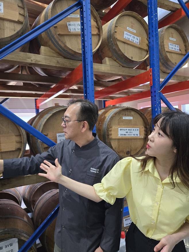 방송인 김민아와 오규섭 온 증류소 대표가 2025년 가을에 출시 예정인 오크통 숙성 소주의 저장고를 구경하고 있다. 온 증류소 제공