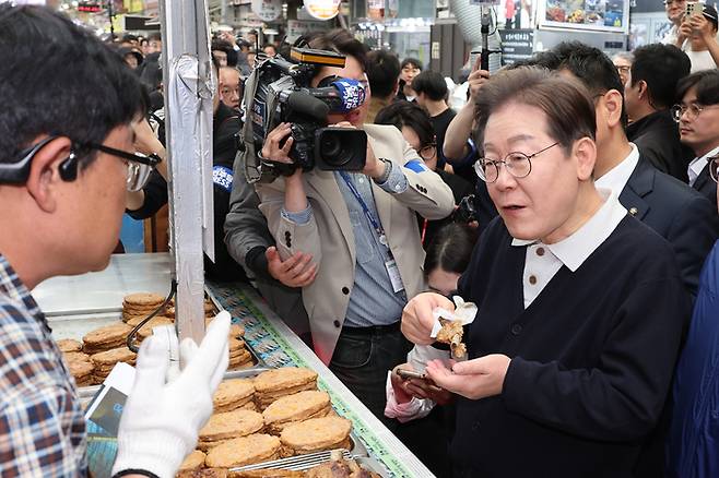 더불어민주당 이재명 대선 후보가 ‘골목골목 경청투어’ : 단양8경편‘에 나선 4일 충북 단양군 단양구경시장에서 떡갈비를 사먹으며 상인과 대화하고 있다. [사진 = 연합뉴스]