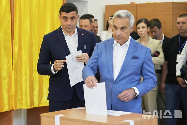 ﻿[모고소아이아(루마니아)=AP/뉴시스] 제1야당 결속동맹(AUR) 대표 제오르제 시미온(38‧왼쪽) 후보가 4일 지난해 11월 대통령 선거 1차 투표에서 선두였던 컬린 제오르제스쿠(63)와 함께 4일 투표하고 있다.2015.05.05.