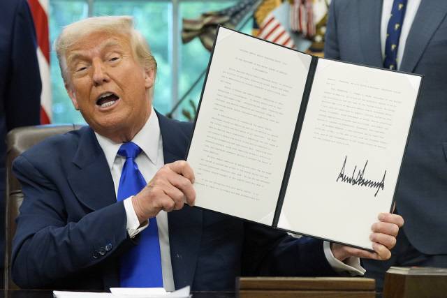 도널드 트럼프 미국 대통령이 5일(현지시간) 워싱턴D.C. 백악관의 오벌 오피스에서 헬스케어 관련 행정명령에 서명한 뒤 이를 들어보이고 있다. AP=연합뉴스