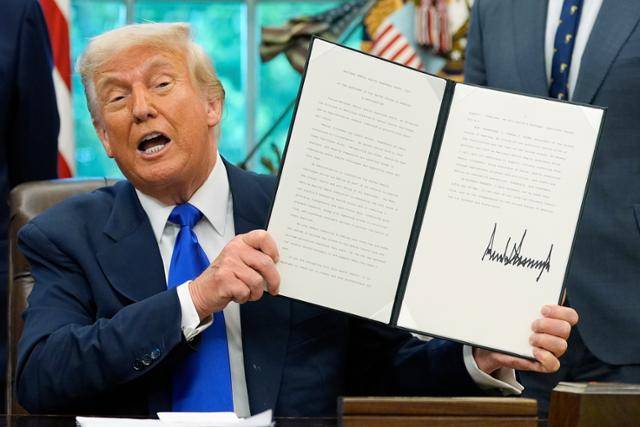도널드 트럼프 미국 대통령이 5일(현지시간) 백악관에서 의약품 제조 촉진 관련 행정명령에 서명한 뒤 문서를 들어 보이고 있다. 워싱턴 AP/연합뉴스.