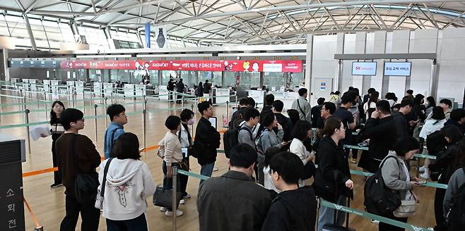 황금연휴를 앞둔 지난달 30일 인천국제공항 제1여객터미널 SK텔레콤 로밍센터에서 출국자들이 유심 교체를 위해 대기하고 있다. 반면 항공사 체크인 카운터는 한산한 모습을 보이고 있다. / 고운호 기자