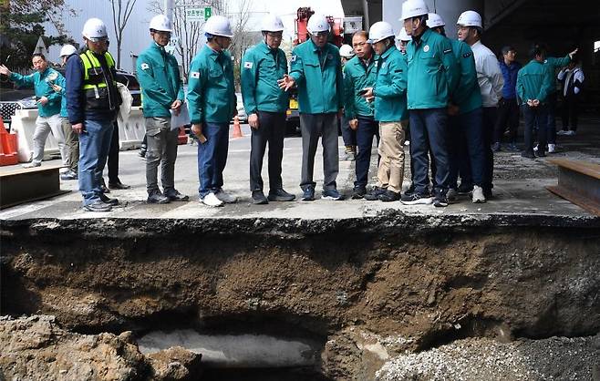 지난달 13일 부산 사상구 학장동 현대자동차 사거리 횡단보도에서 대형 싱크홀이 발생한 가운데 박형준 부산시장(왼쪽 세번째)을 비롯한 관계자들이 현장에서 상태 점검 후 복구 대책에 대해 논의하고 있는 모습. 부산시 제공