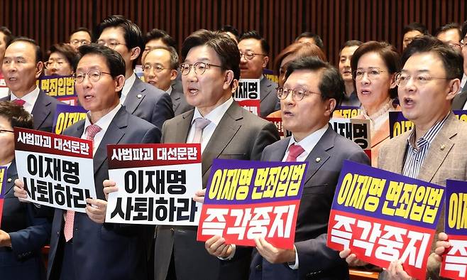 권성동 원내대표(앞줄 가운데)를 비롯한 국민의힘 의원들이 7일 서울 여의도 국회에서 열린 의원총회에서 더불어민주당 주도로 국회 법제사법위원회 법안심사소위원회에서 대통령 당선시 진행 중인 형사재판을 정지하도록 하는 형상소송법 개정안이 통과되자 “이재명 사퇴하라”고 적힌 손팻말을 들고 구호를 외치고 있다. 연합뉴스