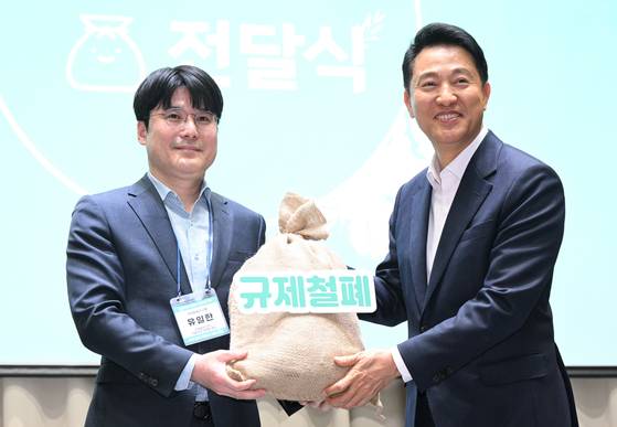 규제철폐 100일 성과보고회에서 시민 제안이 담긴 규제철폐 모래주머니를 전달받고 있는 오세훈 서울시장. [사진 서울시]