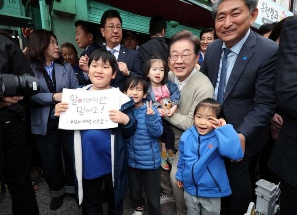 이재명 더불어민주당 대선 후보가 ‘골목골목 경청투어 : 국토종주편‘에 나선 6일 충북 옥천군 옥천공설시장을 찾아 어린이들과 기념촬영을 하고 있다. 이 후보는 어린이날이던 전날 아동수당 지급 연령을 현행 8세에서 18세까지 단계적으로 높이겠다는 공약을 발표했다.  연합뉴스