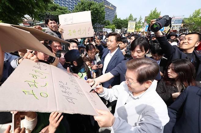 민심을 청취하는 ‘경청 투어’에 나선 이재명 더불어민주당 대선후보가 7일 전북 전주시 완산구 풍남문 인근에서 공판연기를 환영하는 지지자의 응원 피켓에 사인을 해주고 있다. ‘공판연기 환영, 대통령은 국민이 뽑습니다’라고 적힌 피켓에 이 후보는 ‘맞습니다’ 라고 쓰고 있다. 뉴시스