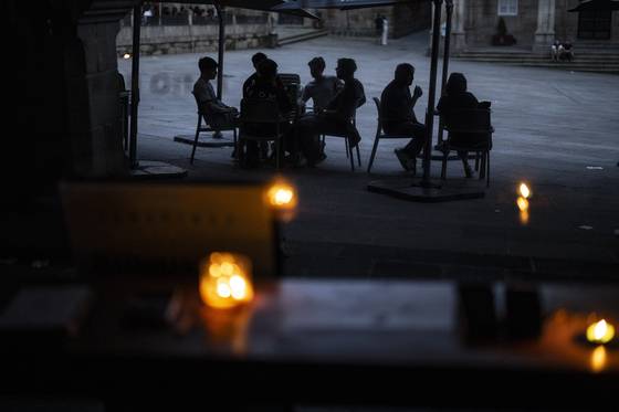 지난달 28일(현지시간) 스페인에서 발생한 대규모 정전 사태로 스페인 북서부 우렌세의 한 펍 내부에 촛불이 켜져 있고 사람들이 야외 의자에 앉아 있다. EPA=연합뉴스
