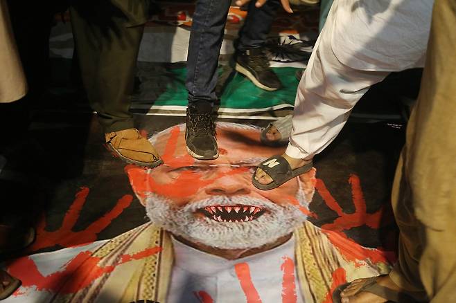 7일(현지시간) 파키스탄 하이베라바드 인도 반대 시위에서 모디 인도 총리 현수막 위에 서 있는 시위대 [AFP]