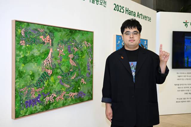 발달장애 화가 조태성 작가가 지난달 23일 서울 중구 하나은행 본점 1층에 전시된 자신의 작품 앞에서 포즈를 취하고 있다. 조태형 기자