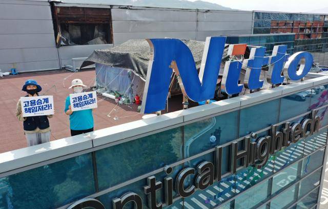 지난달 10일 경북 구미시 한국옵티칼하이테크 고공농성장에서 해고노동자인 박정혜, 소현숙씨가 '고용승계 책임져라'라고 적힌 손피켓을 들고 있다. 소현숙씨는 고공농성 476일 만인 같은 달 27일 건강악화로 땅으로 내려왔고, 박씨가 홀로 싸움을 이어가고 있다. 구미=홍인기 기자
