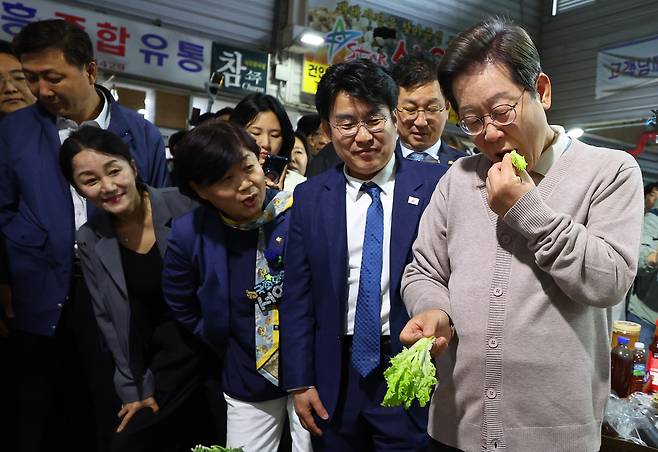 이재명 더불어민주당 대선 후보가 제3차 골목골목 경청투어로 경북지역 방문에 나선 9일 경북 영천시 영천공설시장의 한 가게에서 판매하는 상추를 맛보고 있다. [연합]
