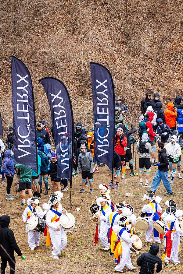 대회 둘째 날, 20km 종목 출발점인 무룡고개에 선수와 응원단이 어우러졌다. 브랜드 깃발 아래 사물놀이패가 인상적이다. 