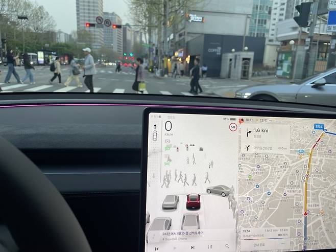 테슬라 차량은 카메라로 주변 사물을 인식하고 디스플레이로 보여준다. 앞에 있는 빨간불 신호등, 횡단보도를 건너는 보행자,  오른편에 끼어들 준비를 하는 차량까지  화면에 뜬 모습. 테슬라는 이 같은 주행 영상 데이터를 AI에 학습시키는 방식으로 자율주행을 구현하려고 한다. /백수전 기자