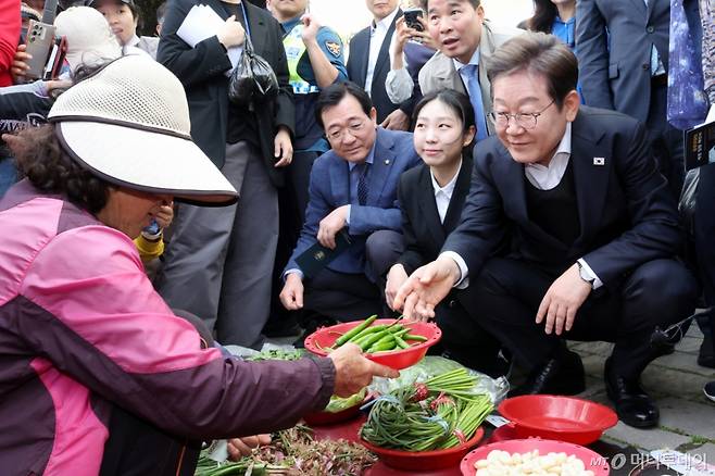 [함안=뉴시스] 조성우 기자 = 민심을 청취하는 '경청 투어'에 나선 이재명 더불어민주당 대선후보가 10일 경남 함안군 가야시장에서 한 상인에게 고추를 구매하고 있다. 2025.05.10. xconfind@newsis.com /사진=조성우