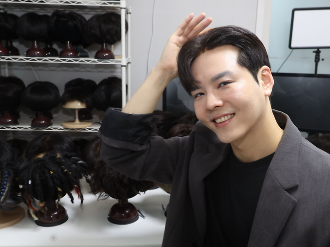 탈모정보 유튜버 최윅(본명 최수호)가 서울 서초구에 위치한 스튜디오에서 자신이 직접 만든 가발들 앞에서 활짝 웃고 있다.을 들어보이고 있다.[이승환 기자]