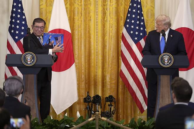 이시바 시게루 일본 총리(왼쪽)가 지난 2월 미국 워싱턴DC 백악관에서 열린 기자회견에서 도널드 트럼프 대통령이 선물한 책을 들어 보이고 있다. [ AP]