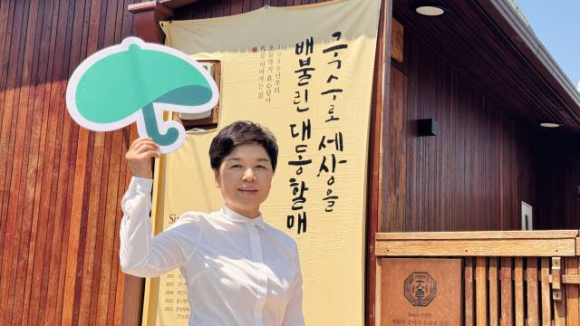 주징청 대동할매국수 대표가 인터뷰를 마친 뒤 초록우산 로고를 펼쳐 보이고 있다.