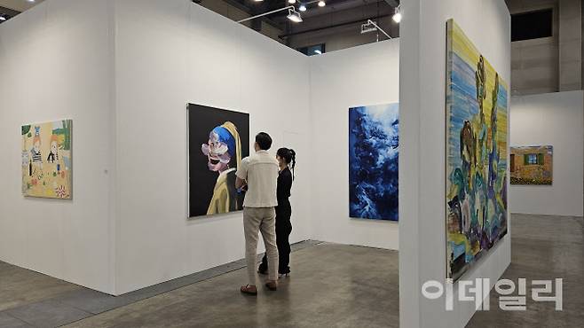 ‘아트부산 2025’ 탕컨템포러리아트 전경. 한 관람객이 갤러리 관계자로부터 중국작가 웨민쥔의 ‘피치 블러섬’(2020)에 대한 설명을 듣고 있다. 이 작품은 첫날 5억원에 팔렸다(사진=오현주 문화전문기자).