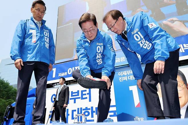 이재명 더불어민주당 대통령 후보가 제21대 대통령선거 공식 선거운동이 시작된 12일 오전 서울 종로구 광화문광장에서 열린 중앙선거대책위원회 출정식에서 운동화를 신고 있다. (공동취재) 뉴스1