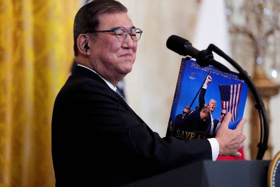 이시바 시게루 일본 총리가 2025년 2월 7일 미국 워싱턴 백악관 이스트룸에서 공동기자회견을 열고 도널드 트럼프 미국 대통령의 선물을 보여주고 있다. 로이터=연합뉴스