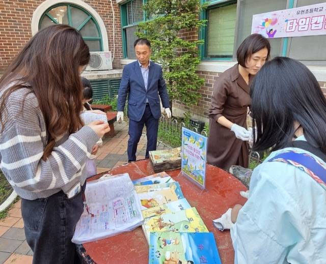 유현초등학교 20년전 졸업생, 재학생, 학부모, 교사들이 타임캡슐에 들어있는 책과 사진 등을 확인하고 있다. 유현초등학교 제공