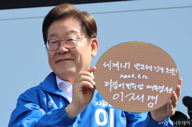 (화성=뉴스1) 안은나 기자 = 이재명 더불어민주당 대통령 후보가 제21대 대통령 선거 공식 선거운동 첫날인 12일 오후 경기 화성시 동탄 센트럴파크 음악분수중앙광장에서 '세계1위! 반도체 강국 도약!'이라고 쓴 반도체 웨이퍼를 들어 보이고 있다. (공동취재)  2025.5.12/뉴스1  Copyright (C) 뉴스1. All rights reserved. 무단 전재 및 재배포,  AI학습 이용 금지. /사진=(화성=뉴스1) 안은나 기자