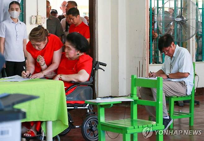 PHILIPPINES-VOTE (일로코스노르테[필리핀] AFP=연합뉴스) 페르디난드 마르코스 필리핀 대통령(오른쪽)과 휠체어에 앉은 모친 이멜다 마르코스가 12일(현지시간) 필리핀 북부 루손섬 일로코스노르테주의 투표소에서 투표하고 있다. 2025.05.12