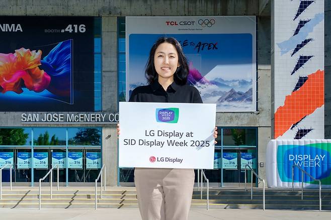 LG디스플레이 직원이 세계 최대 디스플레이 전시회 'SID 2025'가 열리는 미국 새너제이 맥에너리컨벤션센터 앞에서 참가 소식을 알리고 있다./사진=LG디스플레이