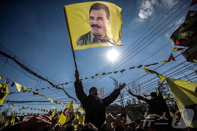 지난 2월15일(현지시간) 시리아 북동부 쿠르드족이 다수 거주하는 도시인 카미슐리에서 열린 1999년부터 튀르키예에 수감돼 있는 쿠르드노동자당(PKK) 지도자 압둘라 외잘란의 석방을 요구하는 시위에서 한 시위자가 그의 초상화가 그려진 깃발을 흔들고 있다. 25.02.15 ⓒ AFP=뉴스1 ⓒ News1 김예슬 기자