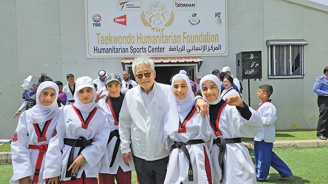 요르단 수도 암만에서 80㎞ 떨어진 곳에 있는 시리아 난민캠프(아즈락)에서 태권도복을 입은 시리아 난민 소녀들이 조정원 총재를 붙잡고 사진을 찍고 있다./아즈락 난민캠프(요르단)=정병선 기자