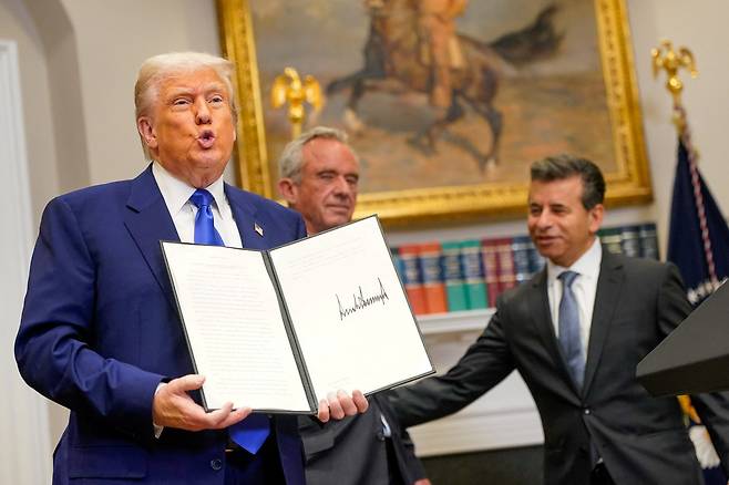 도널드 트럼프 미국 대통령이 12일(현지시각) 워싱턴 D.C. 백악관에서 열린 기자회견에서 약값 인하 관련 행정명령서를 들어 보이고 있다. /로이터·연합뉴스