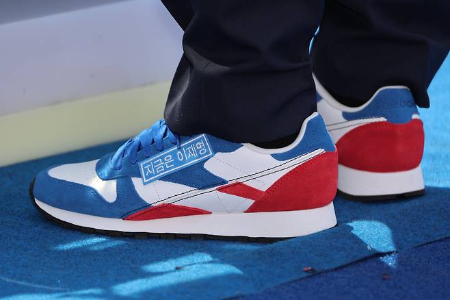 더불어민주당 이재명 대선 후보가 6·3 대통령선거 공식 선거운동 첫날인 12일 서울 광화문 청계광장에서 열린 중앙선대위 출정식 및 첫 유세에서 "지금은 이재명"이라는 문구가 붙은 운동화를 신고 있다. 민주당을 상징하는 청색, 국민의힘을 상징하는 적색이 모두 담겼다. /연합뉴스