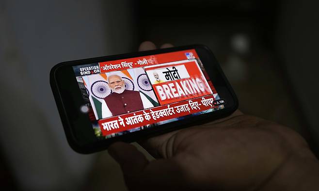 12일(현지시간) 한 남성이 휴대폰으로 모디 인도 총리의 발표를 보고 있다. AP연합뉴스