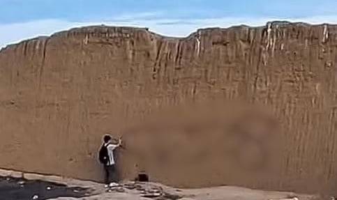 남성으로 추정되는 한 사람이 페루 찬찬 유적지 벽체에 남성 성기 그림을 그리고 있다./데일리메일 캡처