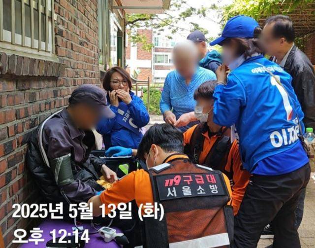"2025년 5월 13일 오후 12시 14분"으로 표기된 사진엔 119구급대가 도착해 쓰러졌던 시민(왼쪽)을 살펴보고 있는 모습이 담겼다. 노연우 의원(왼쪽 두번째)은 휴대폰 통화를 하고 있다. 민병두 전 민주당 의원 페이스북 캡처