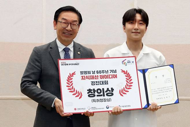 14일 경북대 국제경상관에서 열린 ‘대구경북 지식재산 토크콘서트-IP SHOW’에서 지식재산 아이디어 경진대회 창의상을 수상한 경북대 '고리팀' 대표 한상범 학생에게 상장을 수여한 김완기 특허청장(왼쪽). 특허청