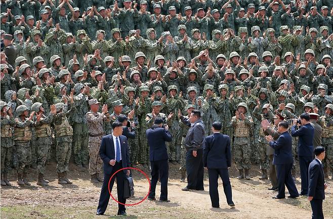 노동당 기관지 노동신문은 특수작전구분대 전술종합훈련과 땅크(전차)병구분대 대항경기, 시범화력협동훈련이 전날 조선인민군 수도방어군단 제60훈련소에서 진행됐다며 김 위원장이 참관했다고 14일 보도했다. 경호원이 ‘경호가방’으로 추정되는 가방을 들고 있는 모습.(붉은색 원) [평양 노동신문=뉴스1]