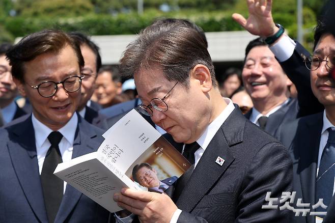 이재명 더불어민주당 대선 후보가 14일 부산 대연동 유엔기념공원 참배를 마친 후 나와 본인 저서에 사인하고 있다. 부산=류영주 기자