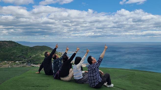 곤륜산 활공장 전망대에 앉아 푸른 바다와 하늘, 그리고 산의 아름다운 풍경을 배경으로 환호성을 지르다.