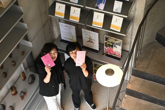 지난 13일 박영숙(왼쪽) 고성도서관 관장과 유소현 팀장이 고성 북카페 ‘퍼슈어리’에 마련된 도서관 큐레이션 전시대 앞에서 책을 들어보이고 있다./어태희 기자/