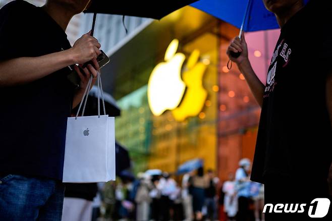 중국 상하이의 한 애플 스토어 앞에서 한 남성이 새 아이폰이 든 쇼핑백을 들고 서 있다. 2023.09.22/ ⓒ 로이터=뉴스1 ⓒ News1 권진영 기자