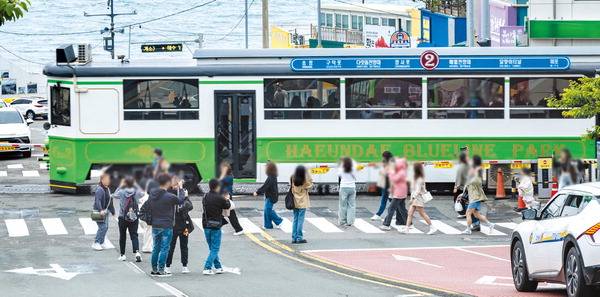 15일 부산 해운대구 청사포에서 해변열차와 바다를 배경으로 사진을 찍으려는 관광객이 도로 한복판까지 침범해 안전사고 우려가 나온다.    이원준 기자 windstorm@kookje.co.kr