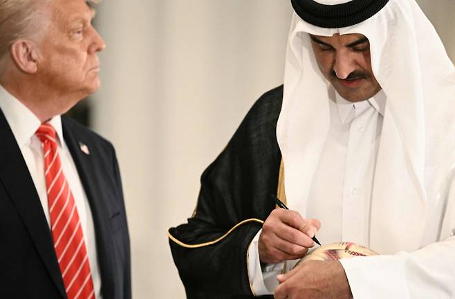 도널드 트럼프 미국 대통령이 14일(현지시간) 도하 루사일 궁전에서 셰이크 타밈 빈 하마드 알사니 카타르 국왕이 월드컵 축구 공에 사인하는 모습을 보고 있다. /AFPBBNews=뉴스1