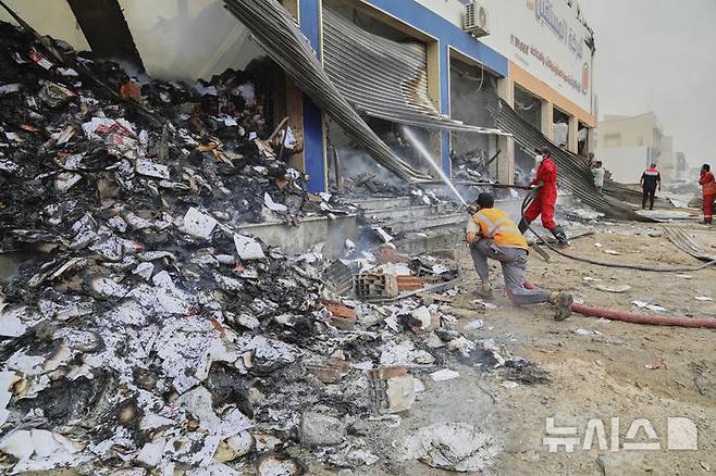 Libyan firefighters put out a fire at a book store at the clashes site between heavily armed militias in Tripoli, Libya, Wednesday, May 14, 2025. (AP Photo/Yousef Murad)