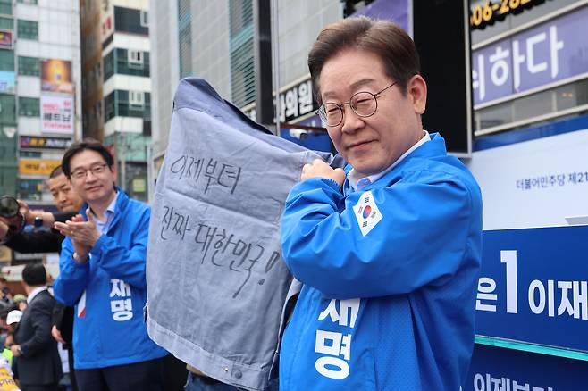 더불어민주당 이재명 대선 후보가 14일 경남 창원시 상남분수광장에서 열린 집중 유세에서 송순호 경남도당위원장으로부터 ‘이제부터 진짜 대한민국!’ 문구가 써진 작업복을 전달받은 뒤 들어보이고 있다. 공동취재